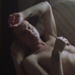 Topless Man Lying on Brown Sofa